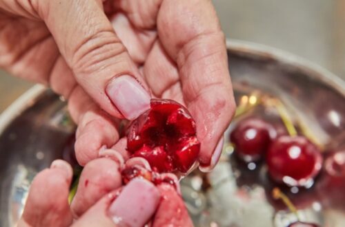 Close-up of a hand gently touching red tart cherries, illustrating the "30 second cheery trick" discussed in the Yu Sleep review about natural deep sleep support.